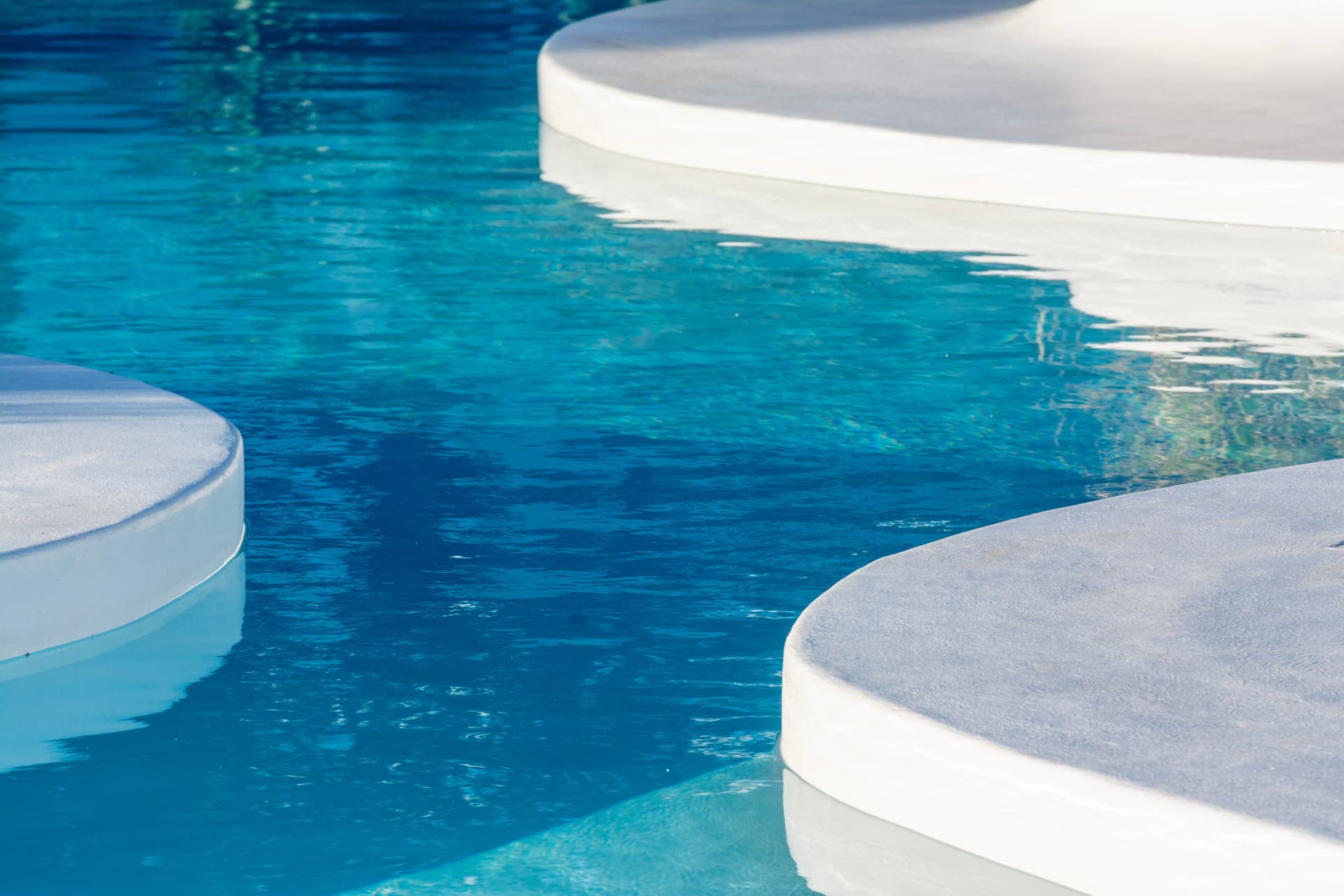The tiled edge and coping of a swimming pool in sunlight.